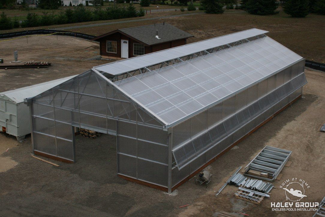 Gable greenhouse with translucent panels and roof vents during construction